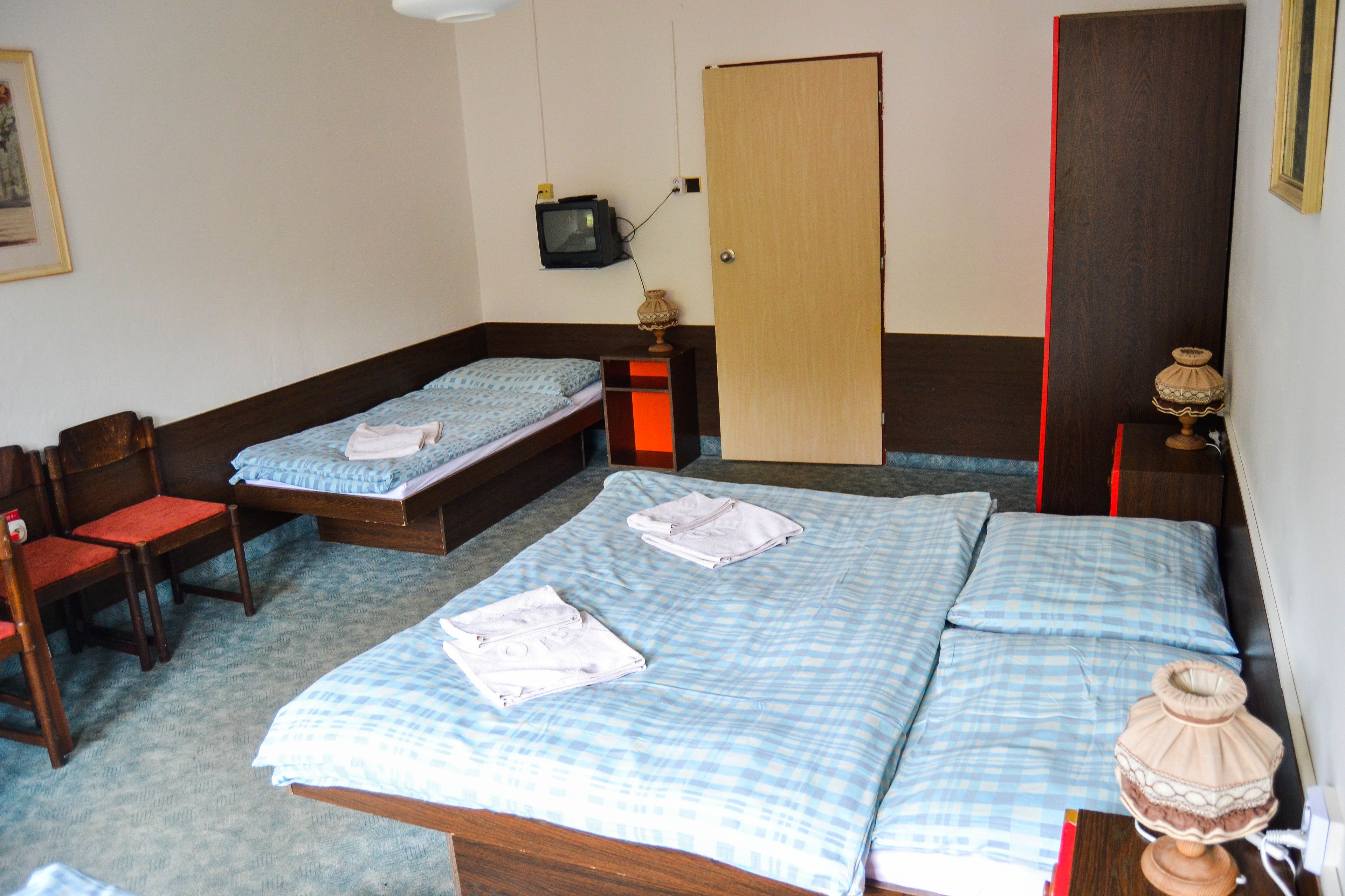 A room with two beds, a chair, a television, and a door.