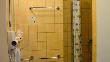 Une salle de bain avec des carreaux jaunes, un lavabo blanc, un porte-serviettes, un rideau de douche et un appareil de climatisation.