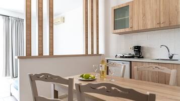 Una cocina moderna con armarios de madera, una mesa de comedor con sillas y una ventana con persianas verticales.