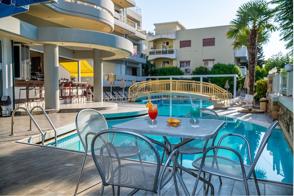 A poolside area with a table, chairs, and a drink.