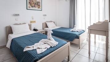 Habitación de hotel con dos camas, una mesita y un cuadro en la pared.