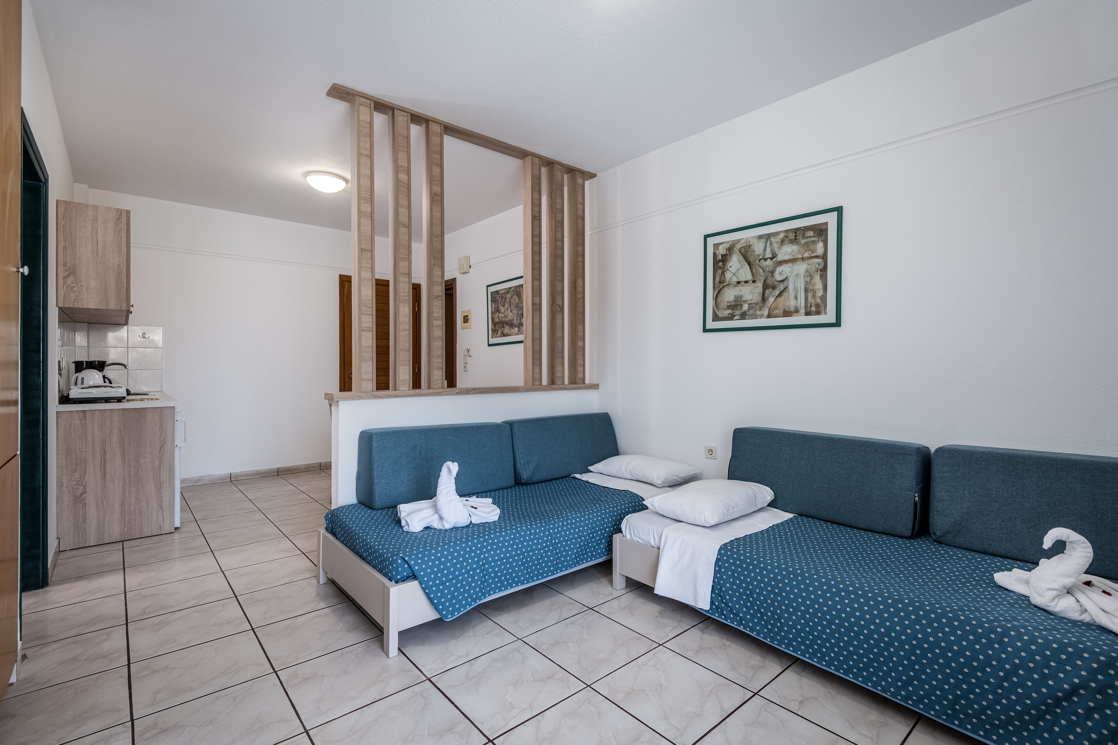 Una habitación de hotel moderna con sofá cama, kitchenette pequeña y un espejo grande.