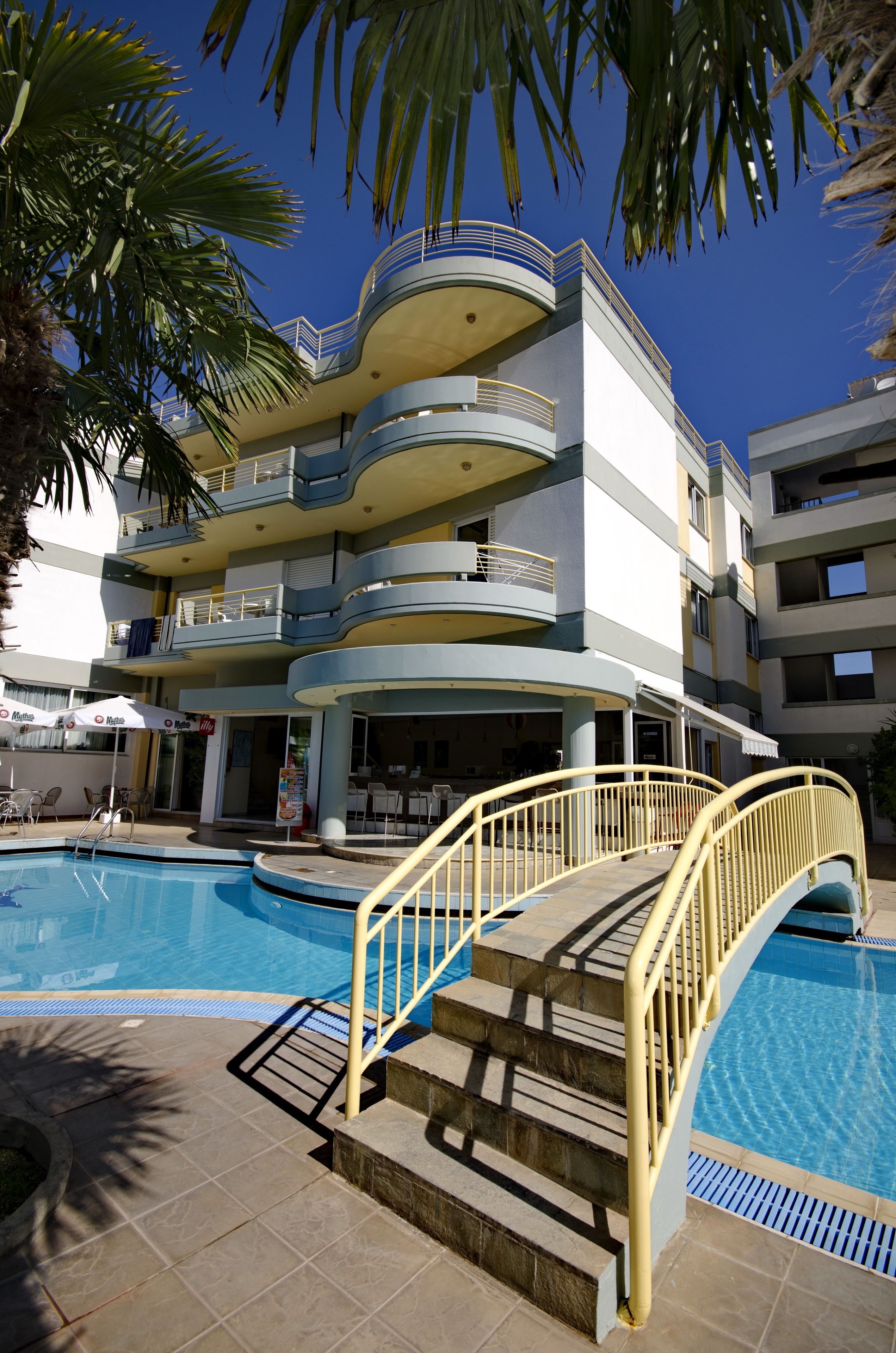 A multi-story hotel with a pool area, including a staircase with a yellow handrail leading to the pool.