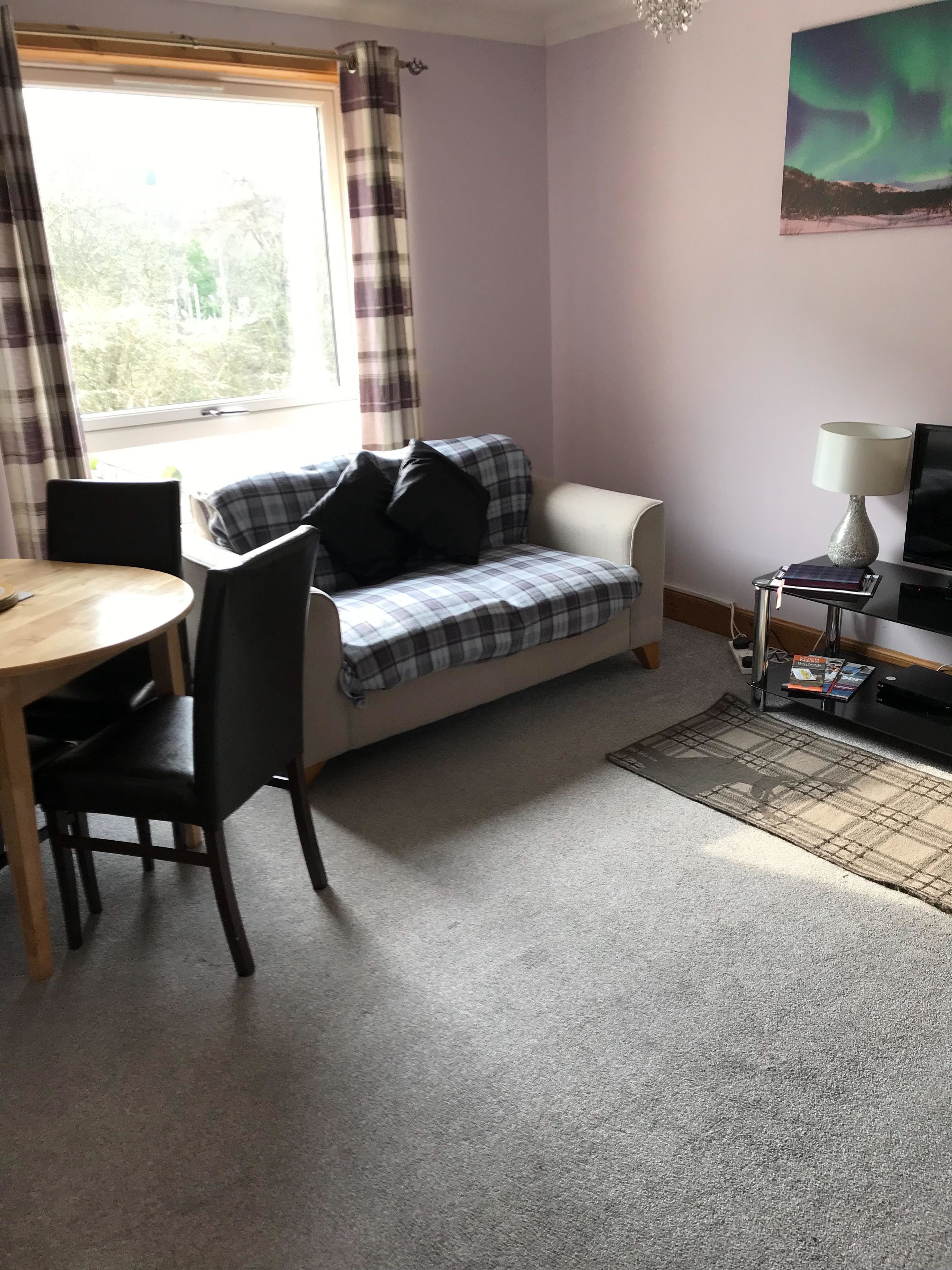 A cozy room with a plaid sofa, a small table, and a TV.