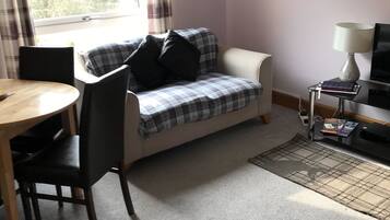 A cozy room with a plaid sofa, a small table, and a TV.