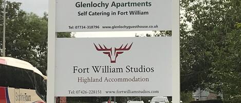 A signboard for Glenlochy Apartments and Fort William Studios, including contact details and website URLs.