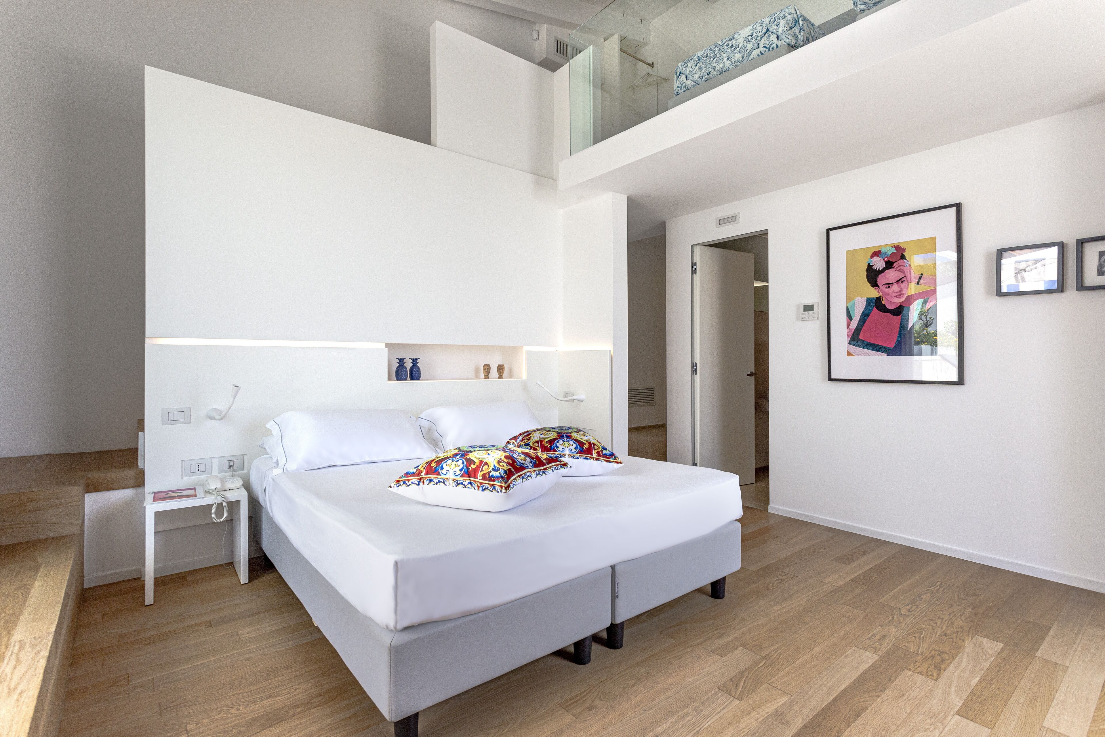 Um quarto moderno com uma cama grande, mesas de cabeceira, um criado-mudo e um quadro emoldurado na parede.