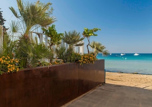 A beachfront hotel with a sandy beach, palm trees, and a clear blue sea. - Calapetra Resort (Syracuse)