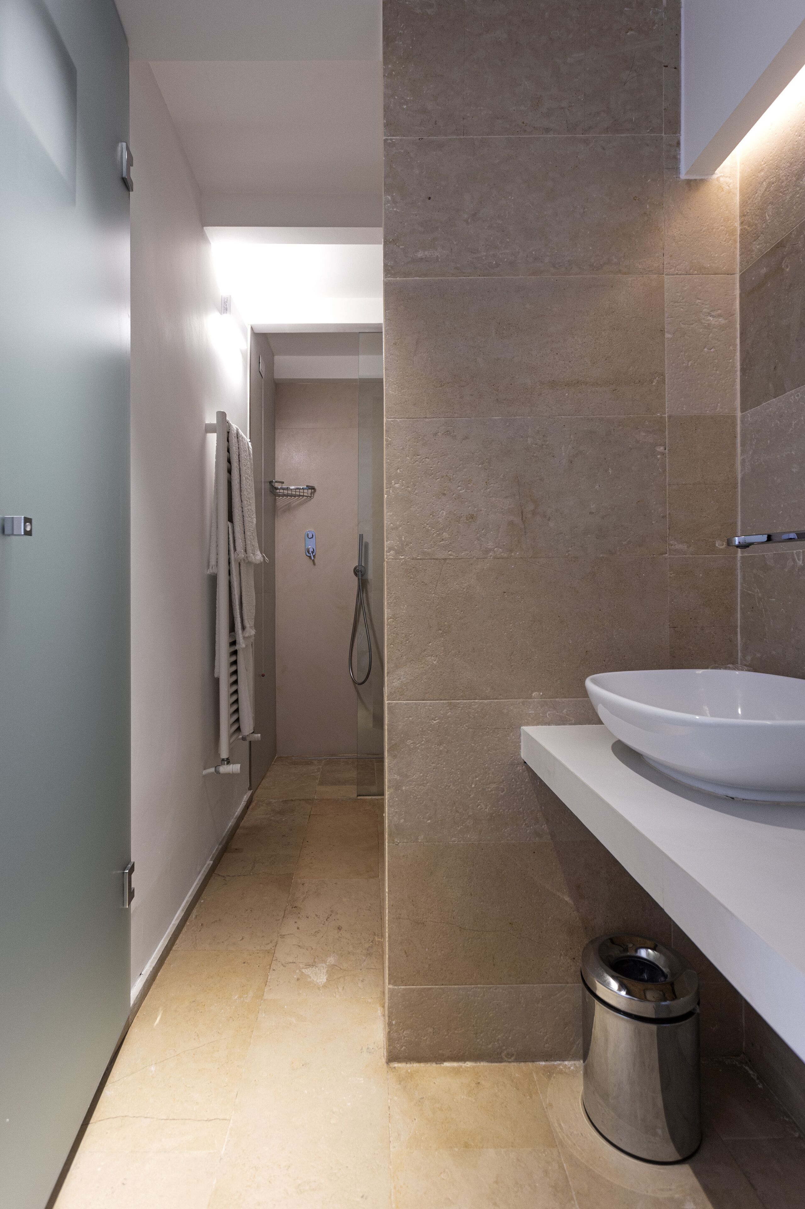 Une salle de bain moderne avec un grand lavabo blanc, une douche et un porte-serviettes.