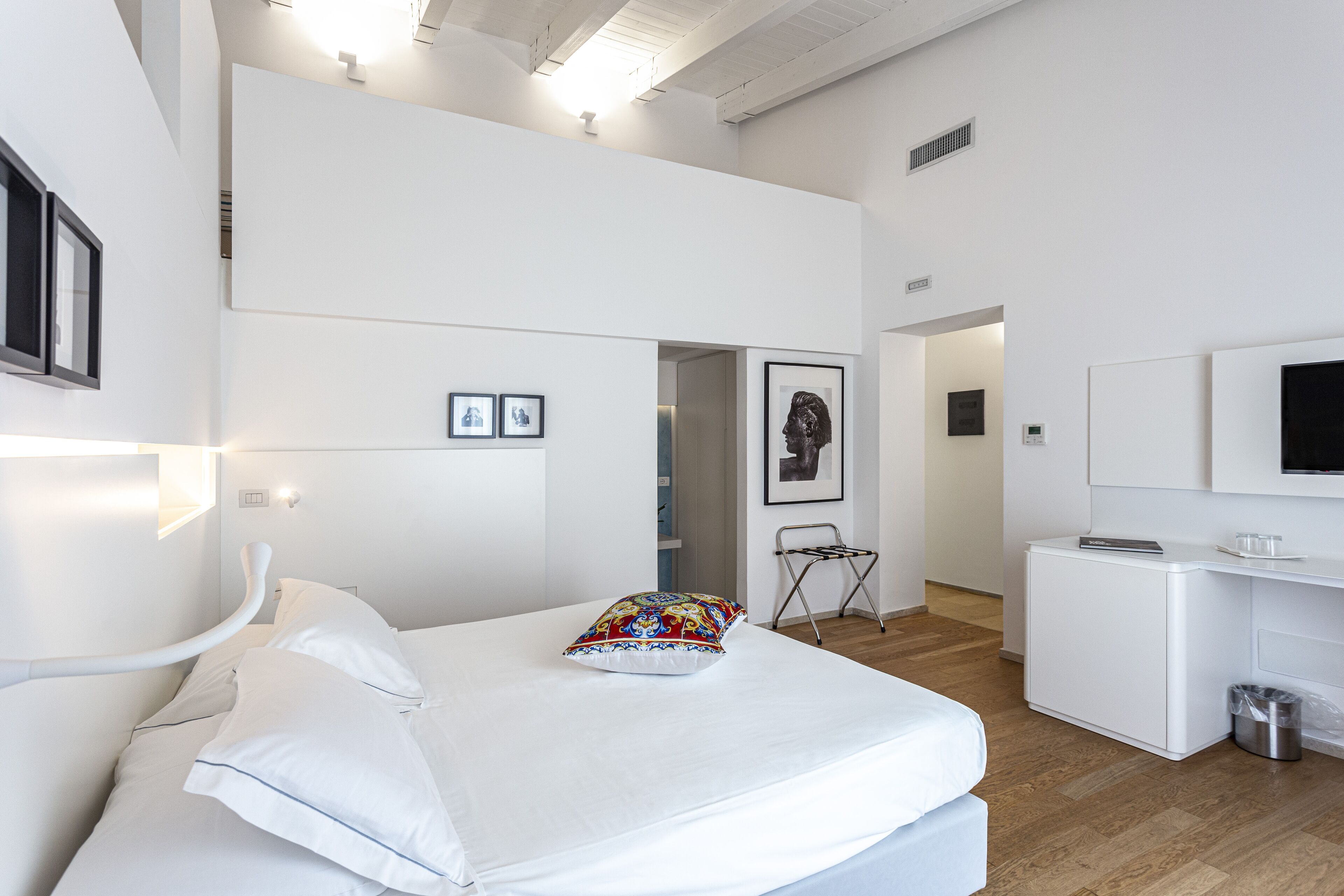 Moderni hotellihuone, jossa on sänky, työpöytä ja televisio.