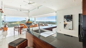 Una cocina moderna con una isla grande, un comedor con vistas y un ventanal que da a un paisaje pintoresco.