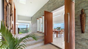 Un interior moderno con pared de piedra, puertas de madera y vista al paisaje.