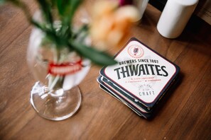 Un conjunto de posavasos de la cervecería Thwaites sobre una mesa de madera.