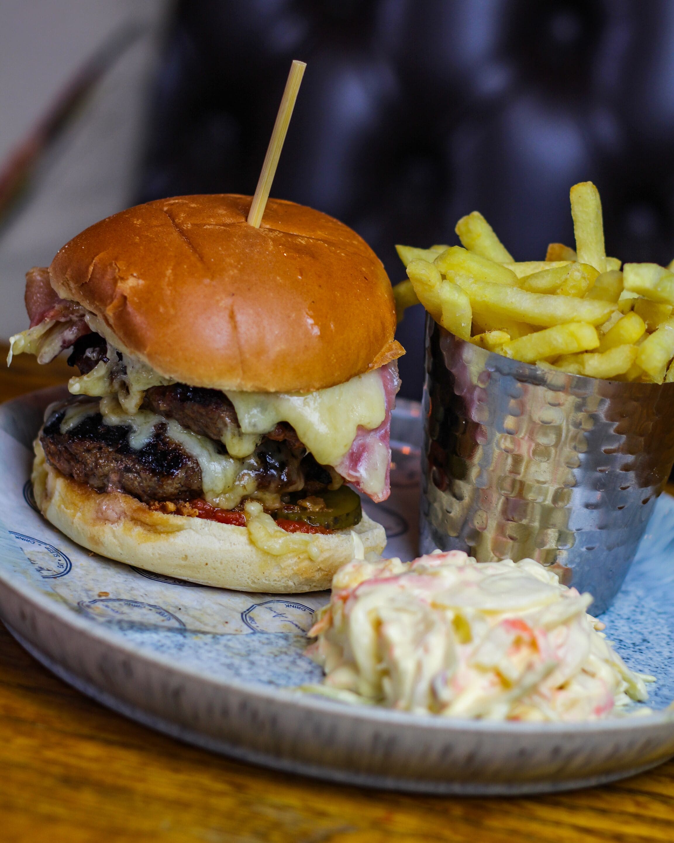 Un plato con una hamburguesa, papas fritas y ensalada de col.