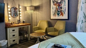 Una habitación de hotel con cama, escritorio, silla, lámpara y un cuadro en la pared.