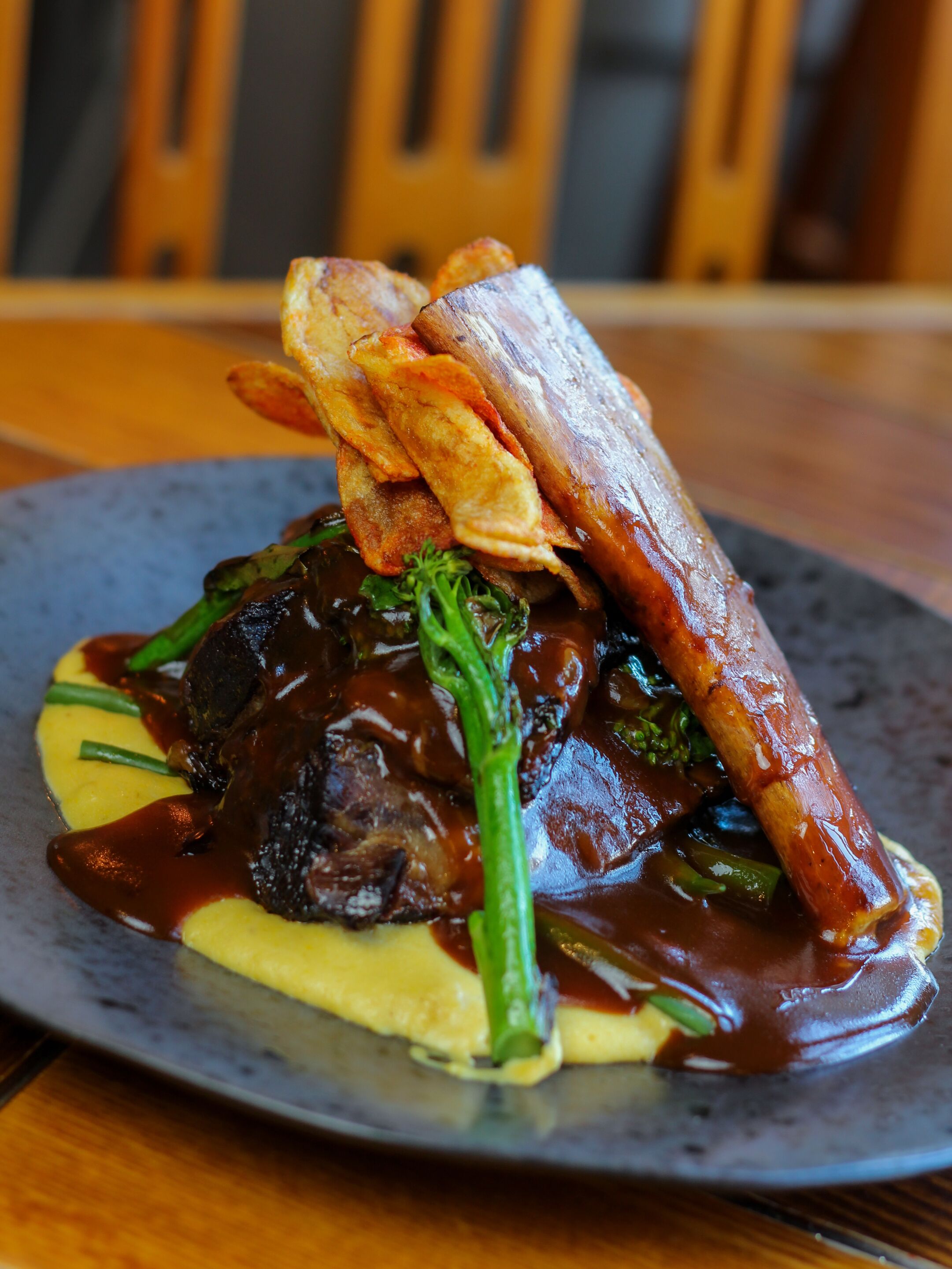 A plate of food with a steak, vegetables, and a piece of meat on top.