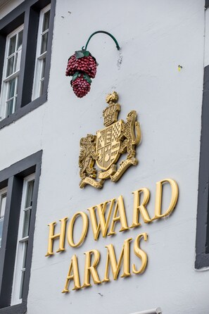 Fachada de edificio con escudo y el nombre "HOWARD ARMS" en letras doradas.