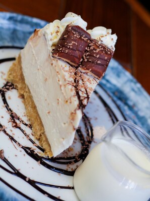 Una porción de pastel de queso con chocolate y crema batida sobre un plato.