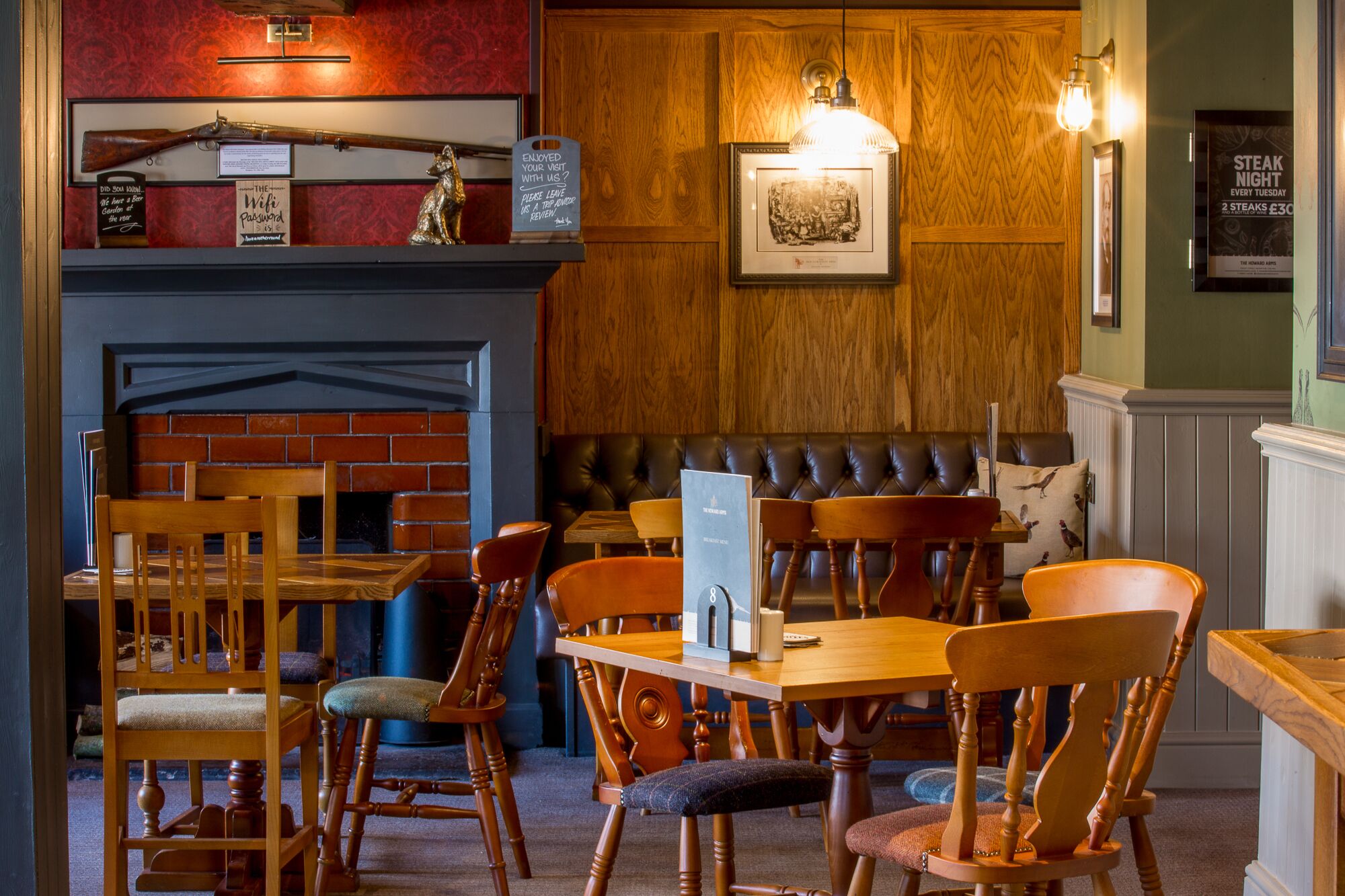 Un restaurant chaleureux, avec des meubles en bois, une cheminée en briques et un tableau affichant le menu.