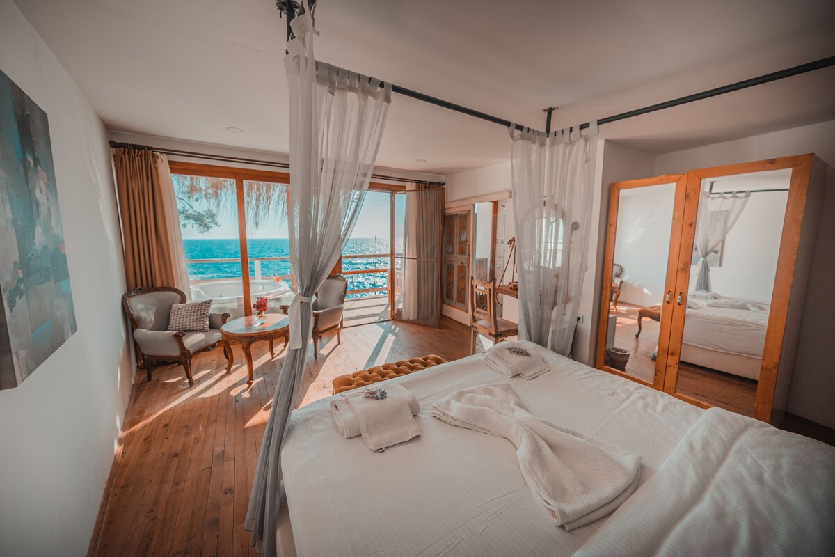 Una camera da letto con un letto grande, una sedia, un tavolino e vista sul mare.