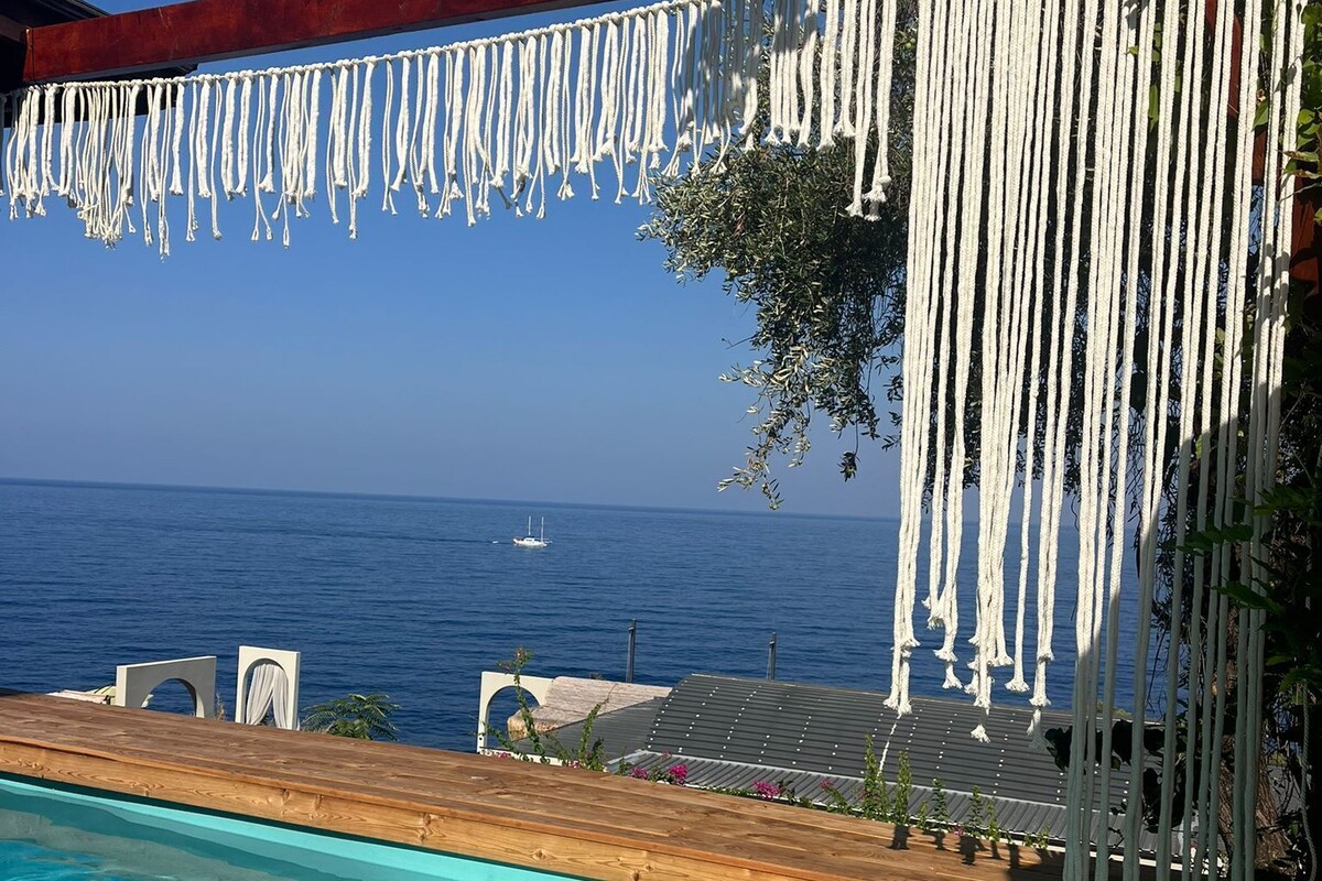 Una piscina con acqua cristallina, un pontile in legno e vista sul mare.