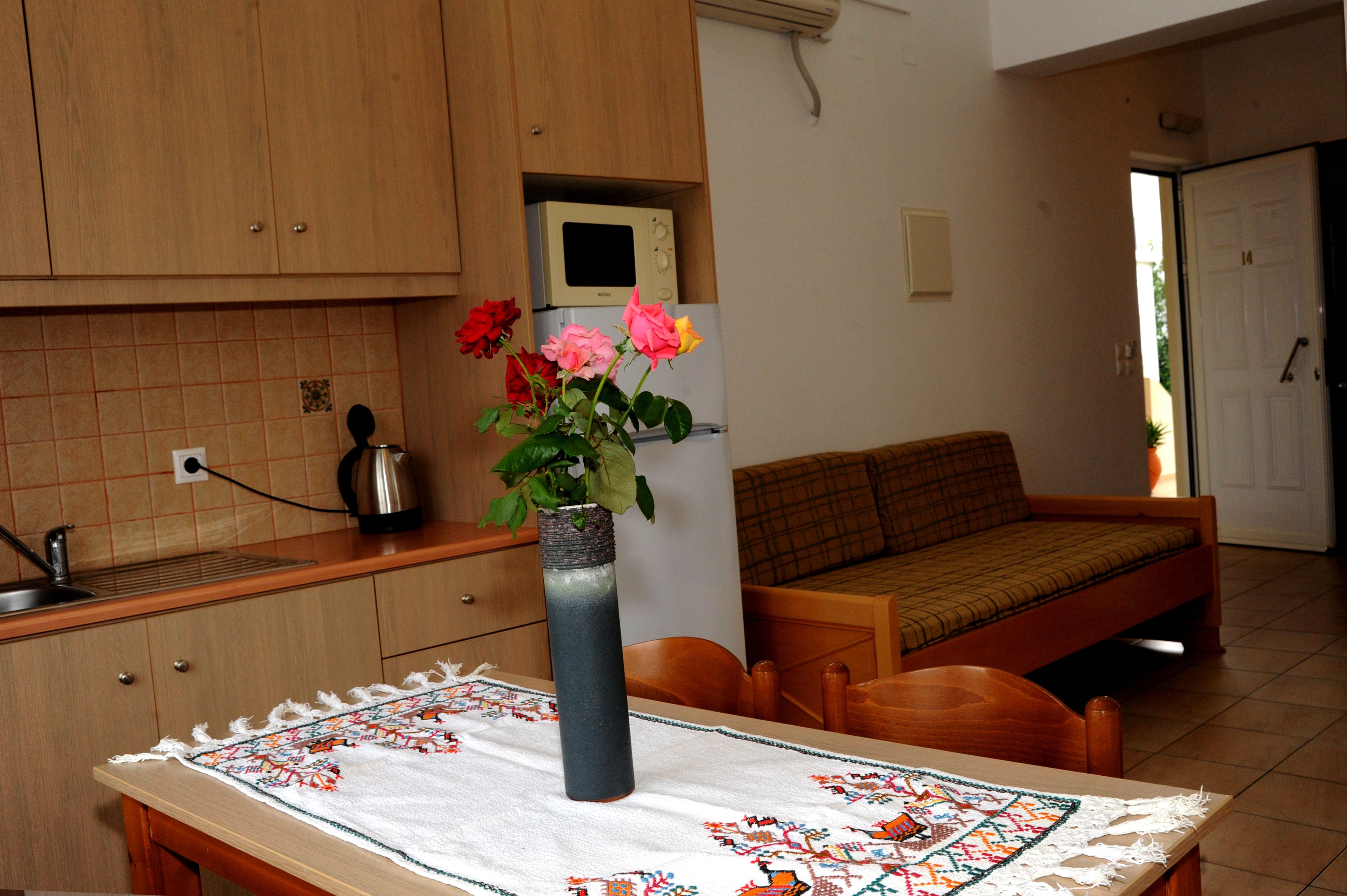 A kitchen with wooden cabinets, a microwave, a sink, and a table with a decorative tablecloth.