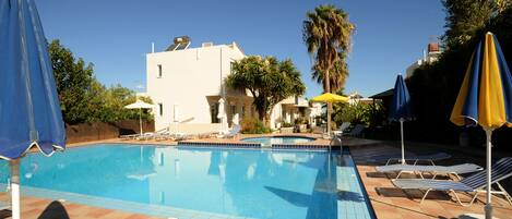 Alberca al aire libre, sombrillas en la alberca y camastros