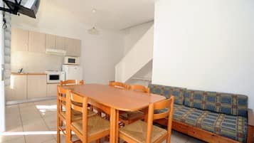 Un espacio habitable compacto con comedor, kitchenette y sofá.