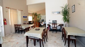 A dining area with multiple tables and chairs, a fire extinguisher, and a potted plant. - Evilion Hotel (Chania)
