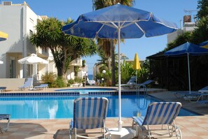 Una piscina al aire libre, sombrillas, tumbonas