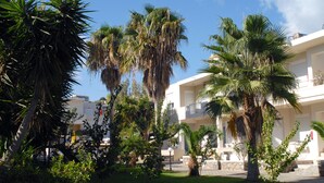 A courtyard with palm trees and a building with balconies. - Evilion Hotel (Chania)
