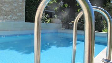 Una piscina al aire libre, sombrillas, sillones reclinables de piscina