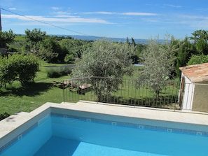 A swimming pool with a view of a garden and distant hills.