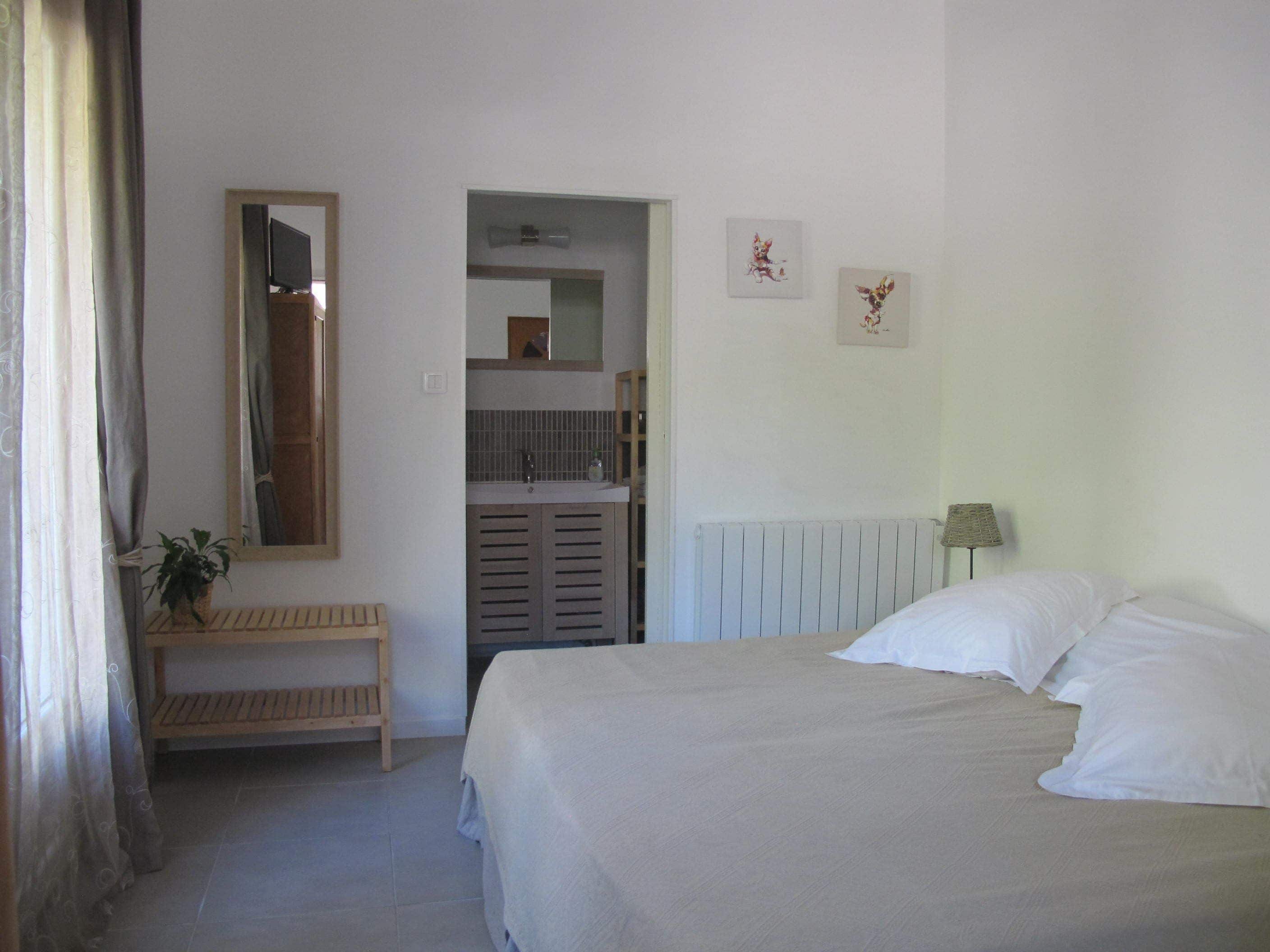 Una camera da letto con un letto, un comodino, uno specchio, un termosifone e una piccola pianta.