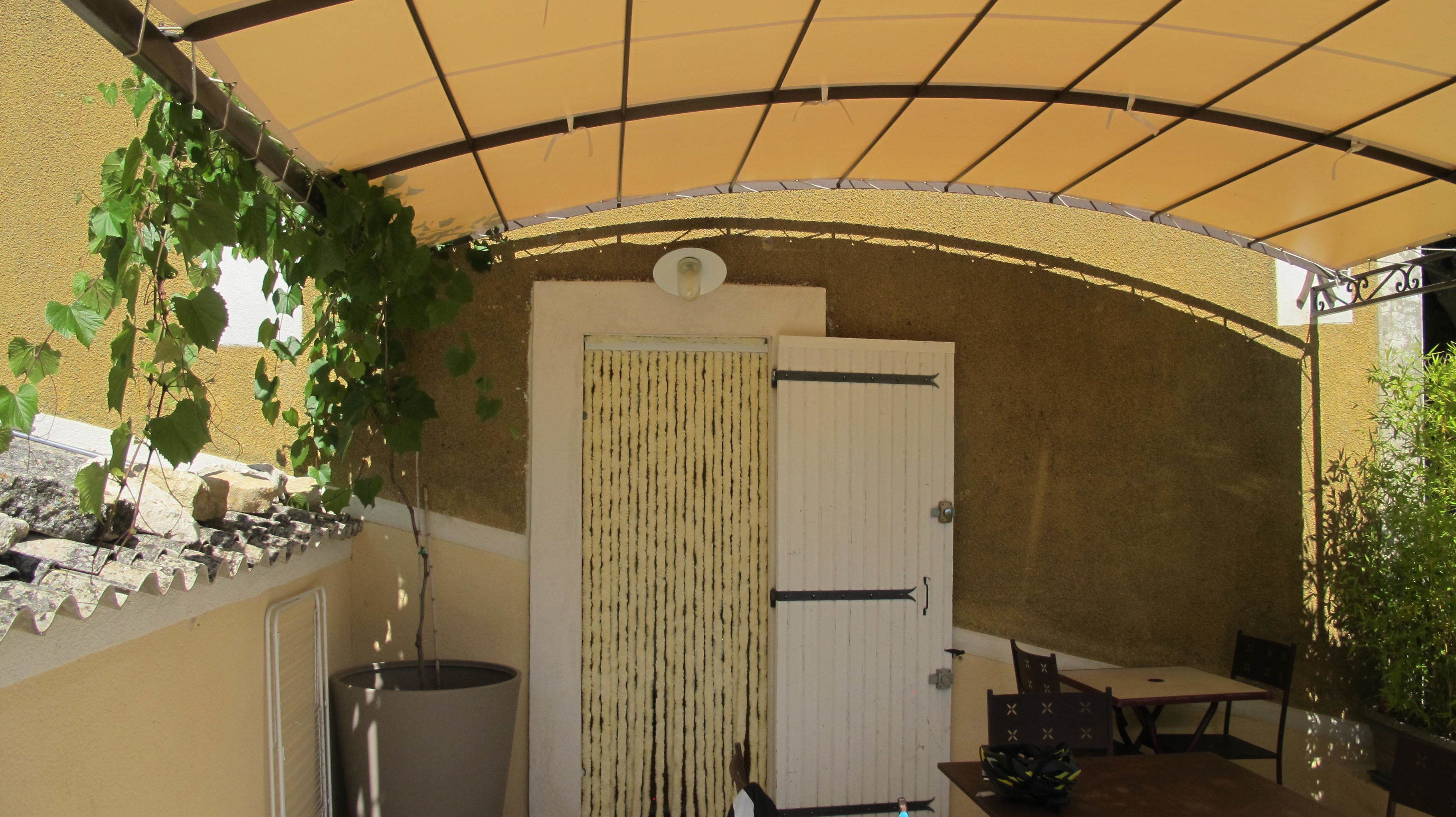 A covered patio area with a door, a trash bin, and a table with chairs.