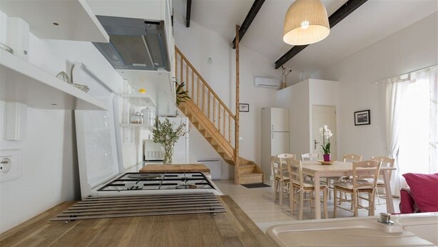 A modern kitchen with a gas stove, wooden flooring, a dining area with a table and chairs, and a staircase. - Loucardalines (Bedoin)