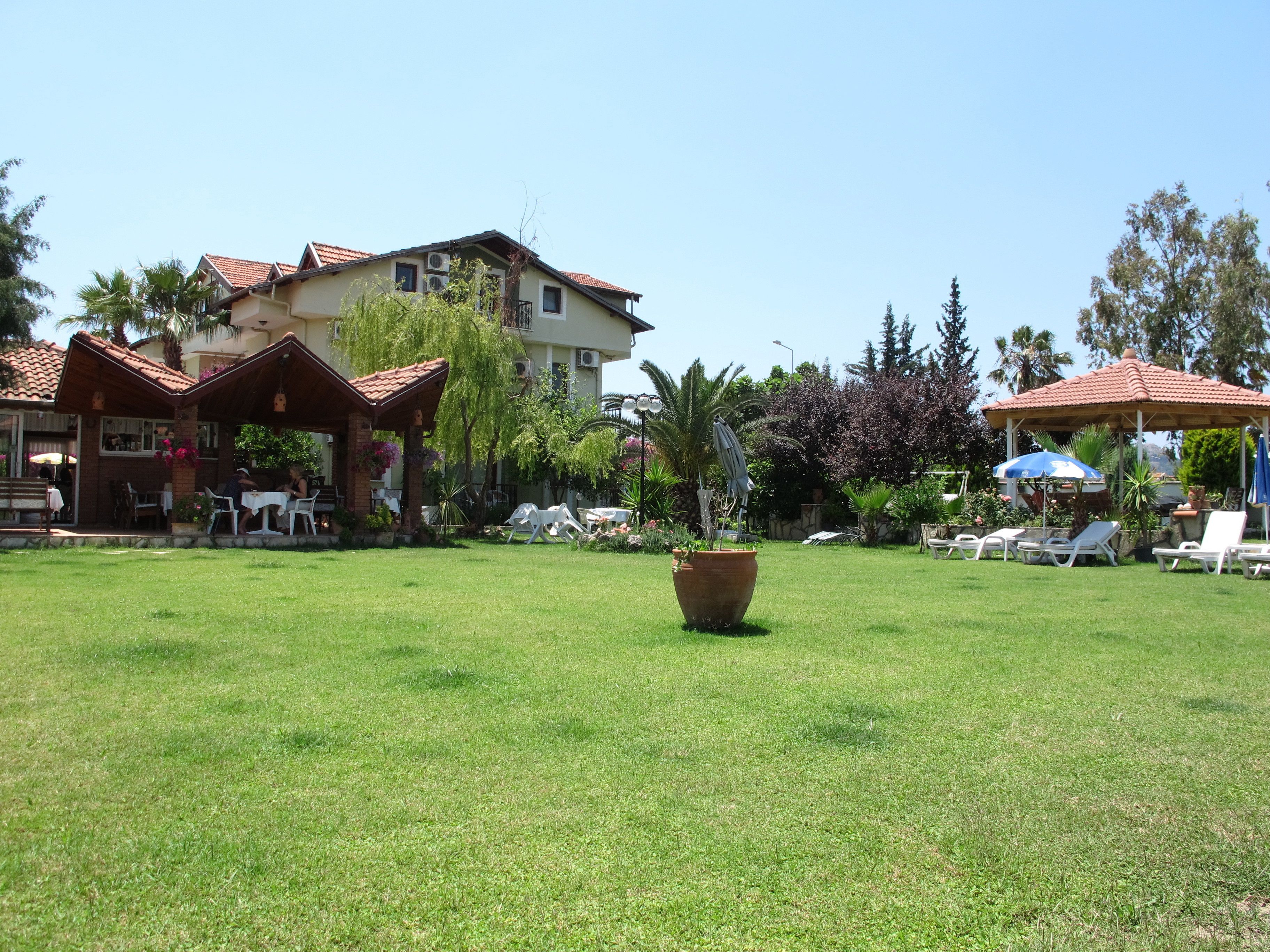 A courtyard with a large lawn, outdoor seating, and a building with multiple balconies.