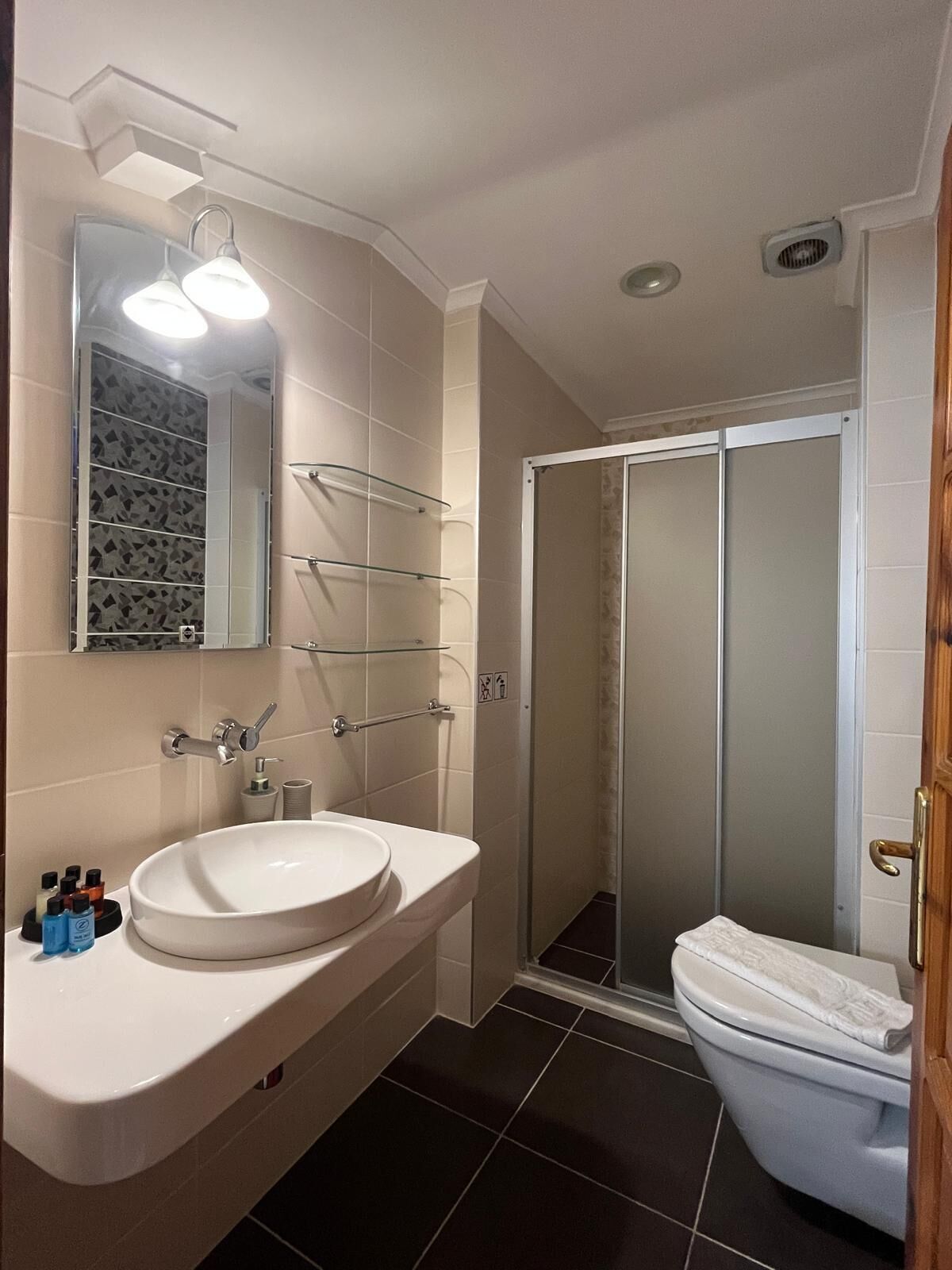 A bathroom with a white sink, mirror, and glass shower enclosure.
