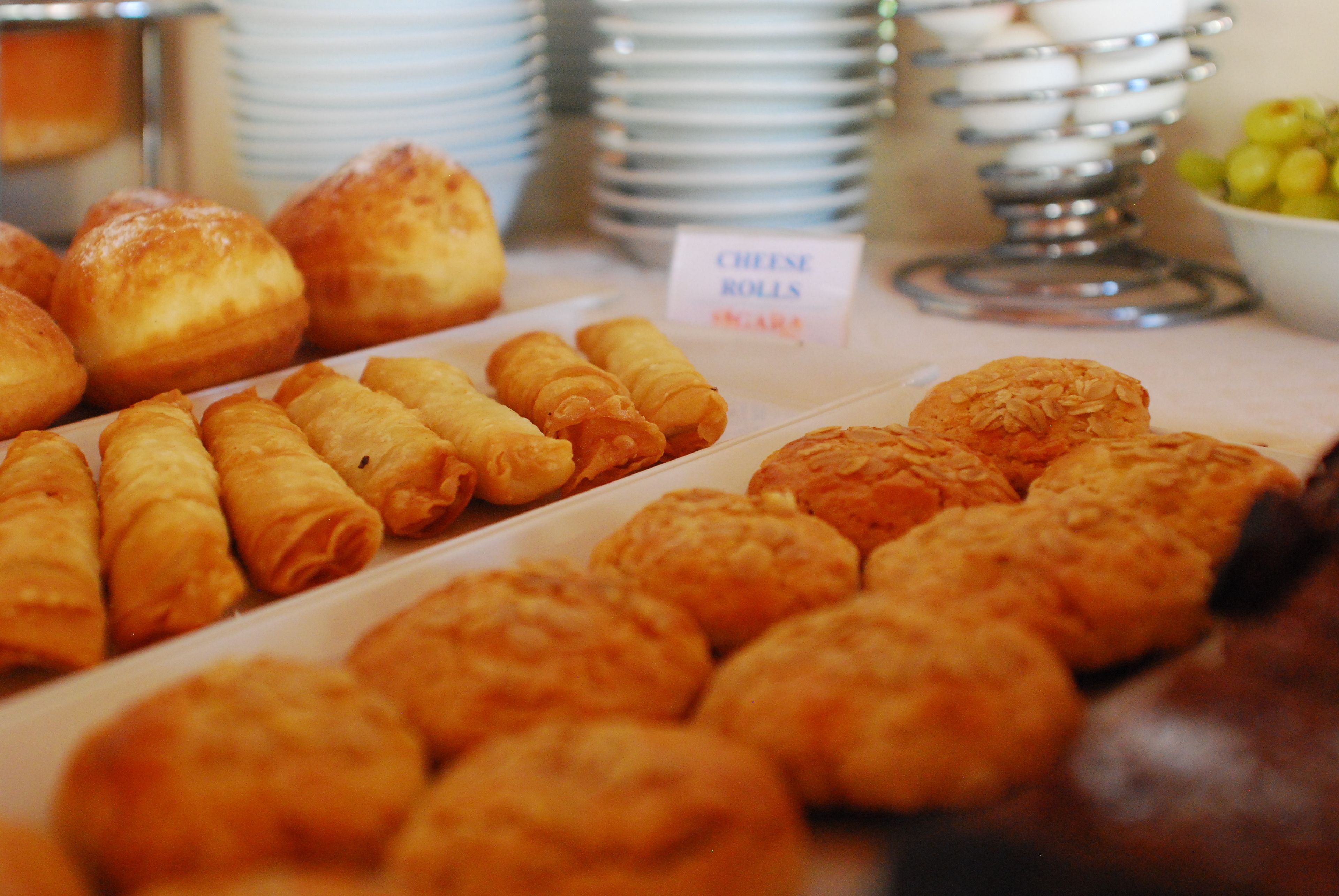 A variety of pastries including cheese rolls and other baked goods displayed on a counter.