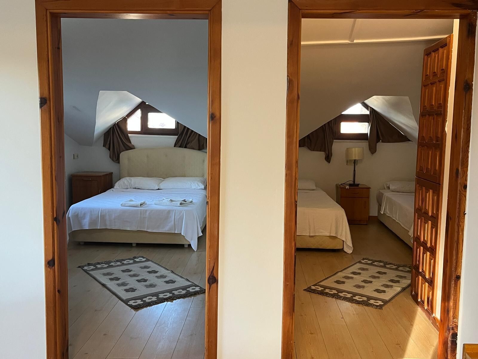 A bedroom with a bed, bedside table, lamp, and a window with curtains.
