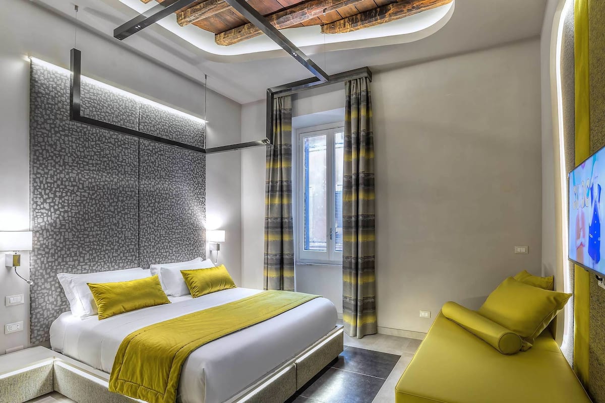 A modern hotel room with a large bed, a seating area, and a TV.