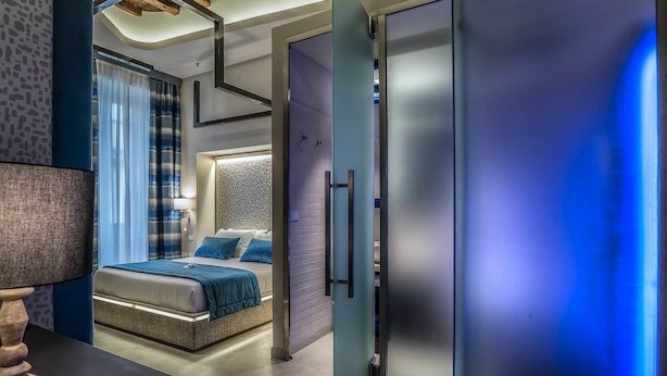A modern bedroom with a bed, a nightstand, and a lamp. - Barberini Luxury (Rome)