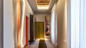 A modern hallway with a wooden ceiling, a long black carpet, and a green door at the end. - Barberini Luxury (Rome)