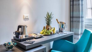 A modern hotel room with a breakfast setup including a coffee maker, a fruit bowl, and a wine glass. - Barberini Luxury (Rome)