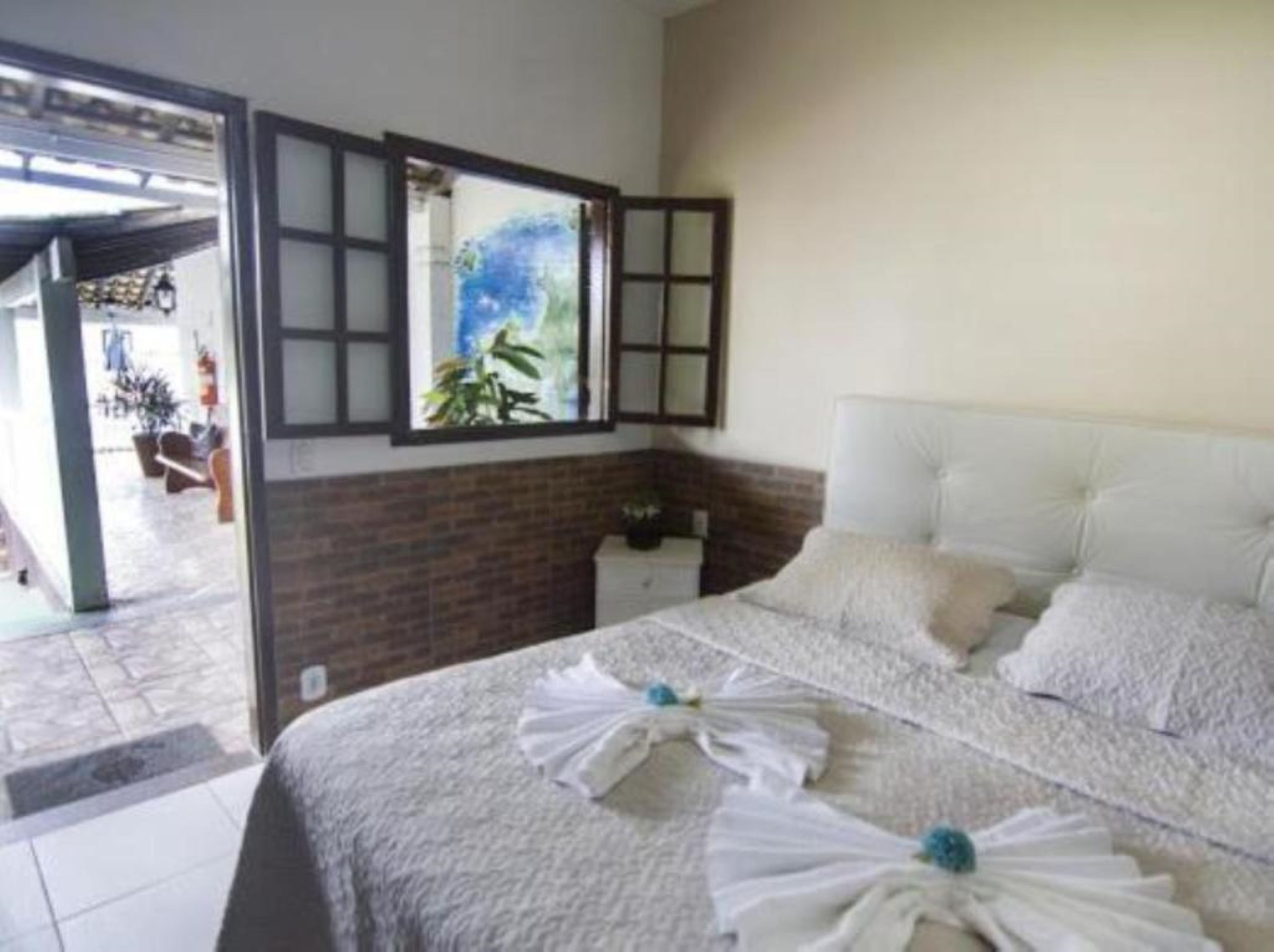 A hotel room with a bed, a window with a view, and a door leading to an outdoor area.