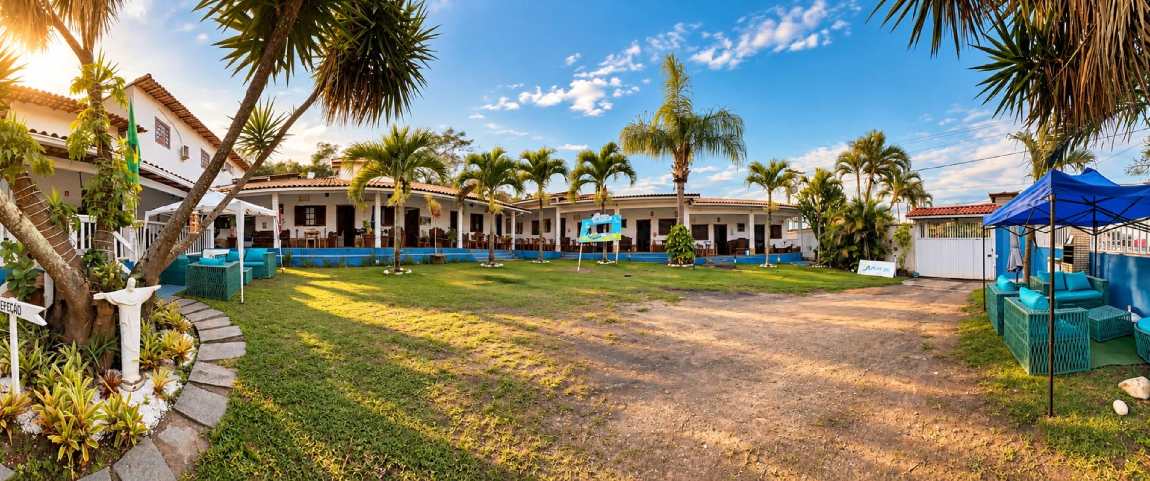 A courtyard with a white building, palm trees, and a blue sign.