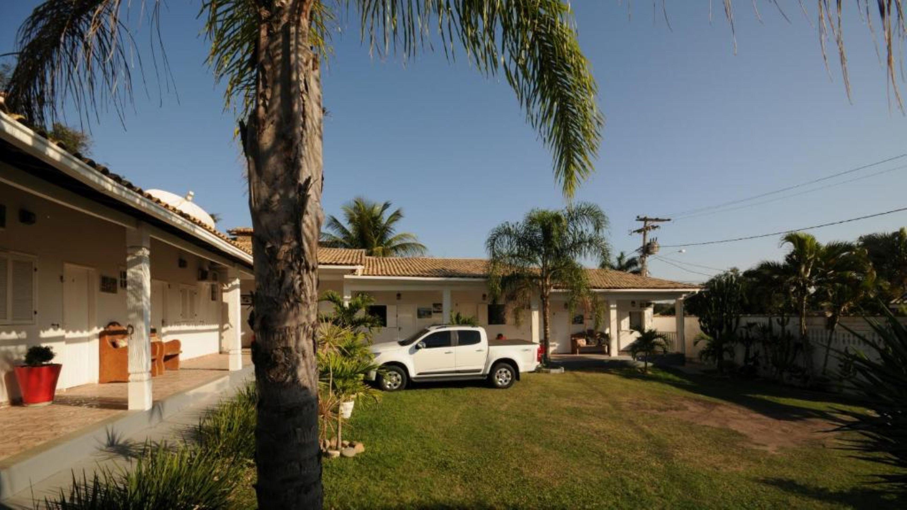 A residential property with a white pickup truck parked in the driveway, surrounded by palm trees and a well-maintained lawn.