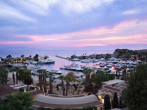 A marina with boats docked, surrounded by buildings and palm trees. - Sani Dunes (Kassandra)