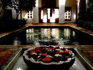 A pool with a flower arrangement in the foreground. - Riad El Mezouar (Marrakech)