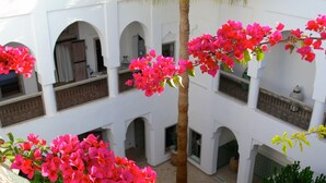 A courtyard with white walls, multiple arches, and pink bougainvillea flowers. - Riad El Mezouar (Marrakech)